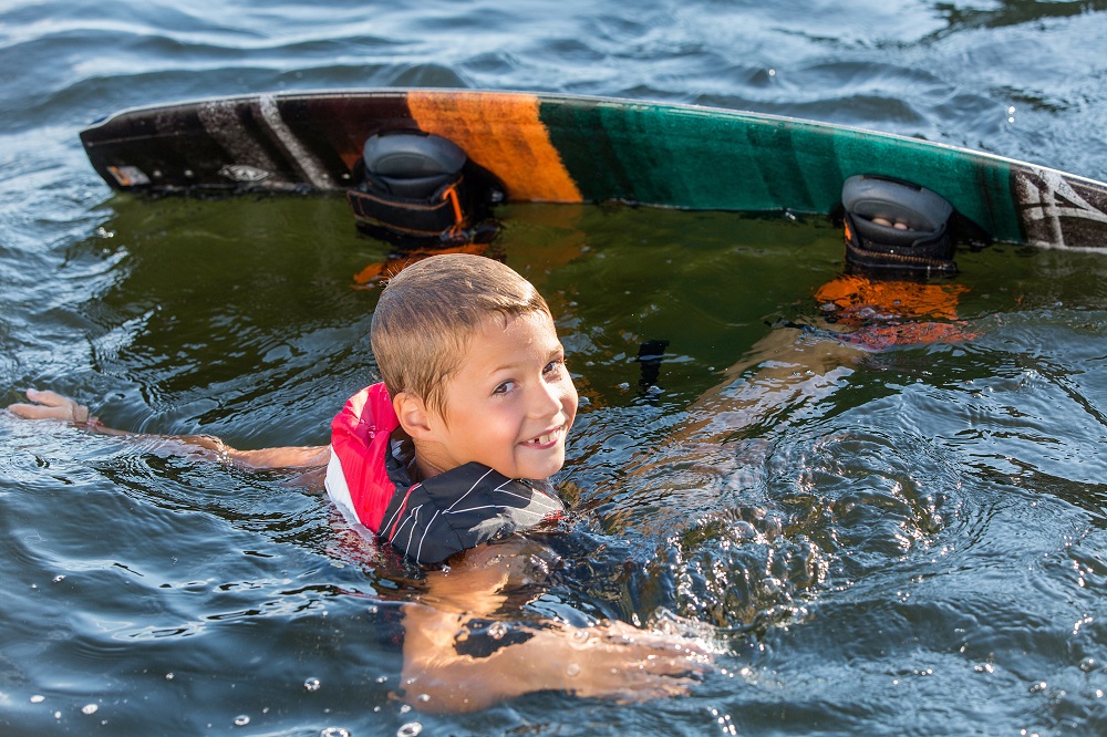 Chłopiec w wodzie z deską wakeboardową.