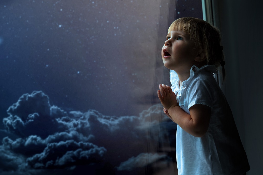 Dziecko patrzy przez okno na niebo